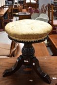 A Victorian mahogany piano type stool having buttoned seat and triple legs