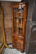 A reproduction glazed mahogany double corner cupboard, of serpentine form with lancet shaped glazing