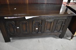 A reproduction carved oak blanket box, of hinged rectangular form with carved panels and incised