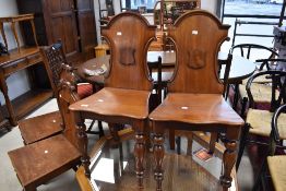TWO pairs of 19th Century mahogany hall chairs having shaped shield backs
