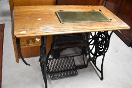 A vintage Singer sewing machine table converted to desk, having oak top and cast iron frame