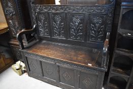A period oak box settle, with carved panels to back and front , scroll arms and lift seat, width