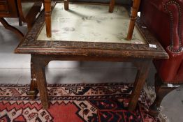 A late 19th or early 20th Century oak coffee table having carved border and embroidered foliate