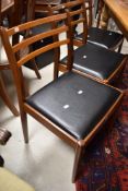 A set of six vintage teak dining chairs having shaped rail backs and drop in vinyl seats