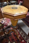 A Victorian walnut pedestal sewing table, of hinged octagonal form with inlaid roundal, the tapering