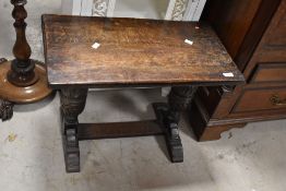 A 20th century reproduction oak occasional table with carved cup-and-cover trestle type ends, 44cm x