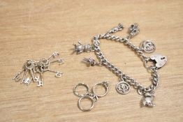 A silver charm bracelet having a padlock clasp and seven charms including football boots and