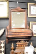 A Victorian walnut wall-mounted mirror with hinged compartment, featuring carved detailing to the