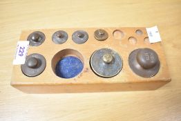 A part set of 20th-century bronze apothecary weights in a wood block case, featuring seven