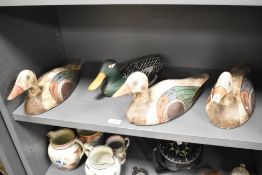 A group of four carved and painted wooden decoy ducks, a drake and three hens painted in