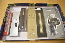 Five ballpoint, rollerball and fountain pens. A Parker Jotter rollerball still sealed in packet, a