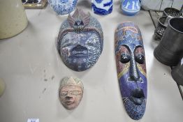 Three 20th-century carved wood decorative masks, to include a colourful Indonesian mask, likely