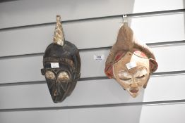 Two 20th-century African Tribal Art hand-carved masks, comprising a male and a female example with