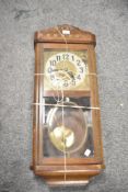 A large 1940s oak-cased pendulum wall clock featuring beaded design to front, complete with key