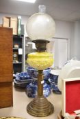 A Victorian brass and yellow milk glass oil lamp, featuring an frosted glass etched orbed-shaped