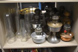 A collection of nine 20th-century Aladdin mantel oil lamps of varying metals, sold together with a