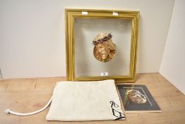 A contemporary religious statuary artwork featuring a gilt sculpture of the face of Jesus Christ