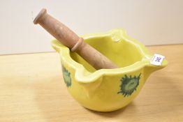 A 20th-century Spanish stoneware mortar with wooden pestle, having a bright yellow glaze with