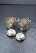 A pair of white metal 800. grade cups, having embossed floral decoration to the body, along with two