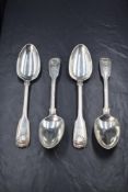 A set of four George III silver fiddle and shell pattern serving spoons, having a castle heraldic