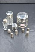 A group of three silver capped glass vanity bottles, of circular form two having canted sides and