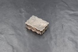 A George V silver snuff box, of hinged rectangular form, having a lobed rim with floral scroll