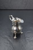 A Georgian silver cream jug, of bulbous form having a Chippendale style rim with generous spout
