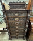 A 19th century oak low countries Wellington chest with a carved back and seven drawers carved with