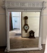 A large white painted overmantle mirror with a wheel pierced cornice