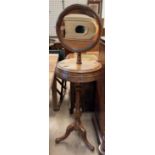 A Victorian oak washstand with a circular framed mirror above two hinged compartments on a reeded