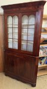 A George III mahogany standing corner cabinet with a moulded cornice above a pair of glazed doors,