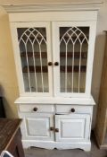 A white painted pine bookcase with a moulded cornice above a pair of glazed doors,