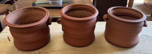 A set of three terracotta planters with pinched handles