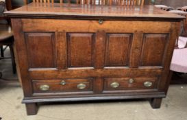 An 18th century oak mule chest with a planked rectangular top above four panels and two drawers on