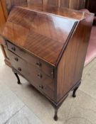 A 20th century mahogany bureau with a sloping fall and three drawers on cabriole legs and pad feet