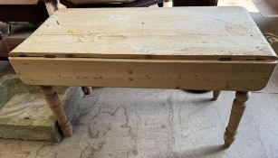 A Victorian pine table with a rectangular top and drop flap on turned legs,