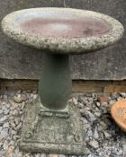 A reconstituted stone bird bath on a square base
