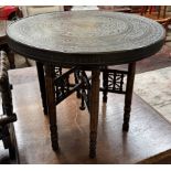 An Indian brass topped table with a folding base