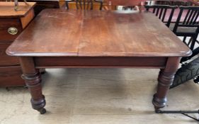 A Victorian mahogany extending dining table on four turned legs and casters