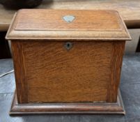 An early 20th century oak stationery cabinet with a hinged front and top enclosing various