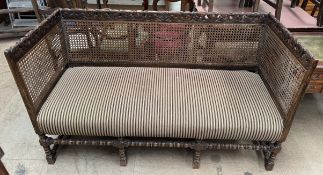 A three seater bergere settee with a scrolling carved rail,