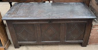An 18th century oak coffer with a planked rectangular top above a three panelled front on stiles,