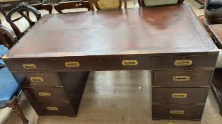 A campaign type pedestal desk with a rectangular top with three drawers and carrying handles to