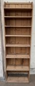 A pine bookcase with a shaped top and eight shelves