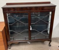 A 20th century mahogany display cabinet with a gadrooned top above a pair of glazed doors with