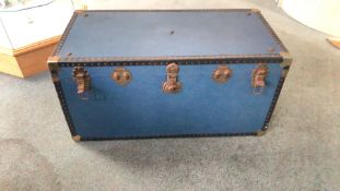 Vintage blue steamer trunk with metal hardware and riveted edges. Features a plaid-lined interior