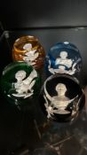 Set of four Baccarat paperweights featuring detailed cameo-style portraits, each in vibrant