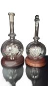 Glass ship decanter pair, displayed on wooden bases, with sailing ship motif encapsulated within