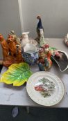 Eclectic ceramic collection featuring clown, peacock, parrot, and meerkat figurines; decorated