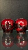 Pair of Royal Doulton flambe small vases featuring a reflective finish. Rounded form. Signed base.